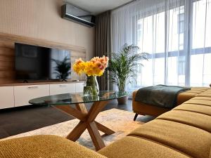 uma sala de estar com uma mesa de vidro com flores em Apartmán Leonardo - city center em Trnava