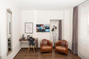 een kamer met 2 stoelen, een bureau en een spiegel bij Boutique Hotel Weisses Kreuz - Adult only Hotel in Luzern