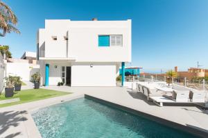 uma casa branca com piscina e cadeiras em Chalet con piscina en Tabaiba by Alterhome em Santa Cruz de Tenerife