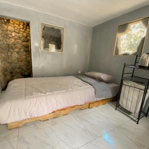 1 cama en un dormitorio con pared de piedra en PALEO Stone Age, en Karangwetan