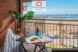 a book on a table on a balcony with a view of the beach at AquaVista Apartament Palamós in Palamós