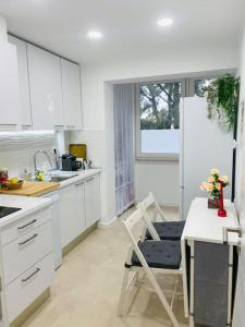 a kitchen with white cabinets and a table and a chair at Modern 3 bedroom Flat in Lisbon in Lisbon