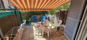 eine Terrasse mit einem Tisch, Stühlen und einem Zaun in der Unterkunft Mazet 5 pers plage parking gratuit wifi clim in La Londe-les-Maures