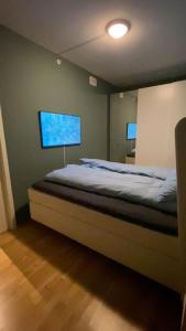 a bedroom with a bed with a large monitor on the wall at Strøken leilighet inkl parkeringskjeller. in Trondheim
