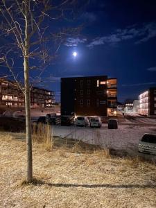 a building with cars parked in a parking lot at night at Strøken leilighet inkl parkeringskjeller. in Trondheim