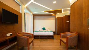 a room with a bed and two chairs and a tv at Escape Resorts Vayalada in Kozhikode