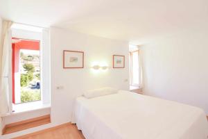 a white bedroom with a white bed and a window at Apartment in Muralla Roja - 0413 in Calpe
