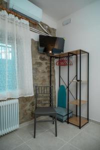 a room with a chair and a shelf and a television at Akratos House in Kastraki