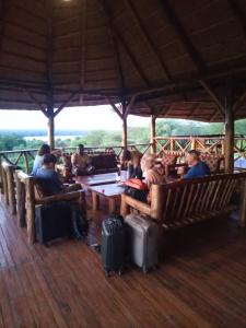 un grupo de personas sentadas en mesas en un pabellón en Elephant View Lodge, en Kasenyi