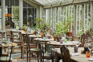 an empty restaurant with tables and chairs and plants at Fern Villa in Lymington