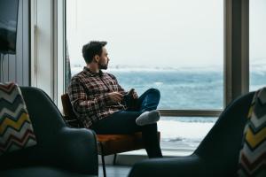 a man sitting in a chair in front of a window at Lofothytter in Offersøya