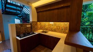 cocina con armarios de madera, fregadero y ventana en Escape Resorts Vayalada en Kozhikode