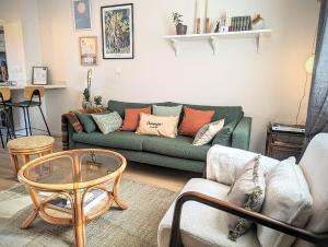 sala de estar con sofá verde y mesa en Le Cémarose: spa, jardin, terrasse et jolie vue au cœur d'Epernay, en Épernay