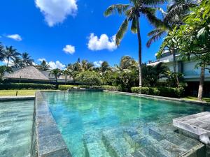 a swimming pool in front of a house with palm trees at Unique Beachfront Appartment in Trou aux Biches