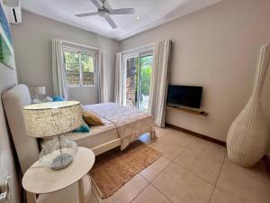 a bedroom with a bed and a tv and windows at Unique Beachfront Appartment in Trou aux Biches