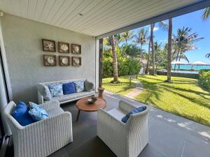 a porch with a couch and chairs and a table at Unique Beachfront Appartment in Trou aux Biches