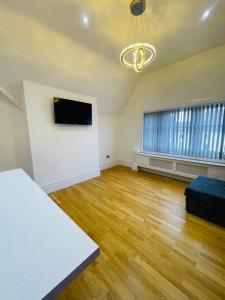 an empty living room with wood floors and a flat screen tv at VIP penthouse own bathroom one bedroom on suite in Wolverhampton