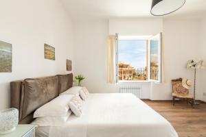 a white bedroom with a large bed and a window at Guest House Maison 6 in Lido di Ostia