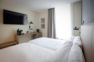 a hotel room with two beds and a flat screen tv at Hotel & Spa Convento San Francisco in Soria