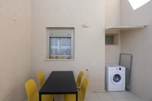 a dining room with a table and yellow chairs and a washing machine at 2BD and 2 Bath duplex on the Hilton beach with a shelter in Tel Aviv