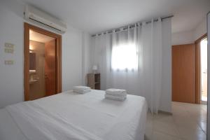 ein weißes Schlafzimmer mit einem Bett mit zwei Handtüchern darauf in der Unterkunft 2BD and 2 Bath duplex on the Hilton beach in Tel Aviv