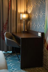 a desk in a hotel room with a chair and a lamp at Hampshire Hotel - Delft Centre in Delft