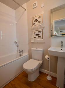 a white bathroom with a toilet and a sink at Tern Quay Cottage, Birdwatching Dream! Crabpot Cottages Sheringham in Cley next the Sea