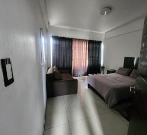 a bedroom with a bed and a couch and a window at Beachurst Apartment in Durban