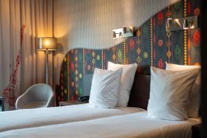 una camera d'albergo con letto e cuscini bianchi di Hampshire Hotel - Delft Centre a Delft