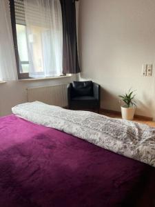 ein Schlafzimmer mit einem lila Bett und einem schwarzen Stuhl in der Unterkunft Entire Flat for you Schwetzingen,Mannheim & HD in Oftersheim