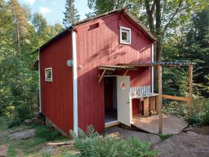 a red shed with a porch and a deck at Gemütliches Tiny House Uggla im Wald am See in Torestorp