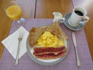 un plato de huevos tocino y tostadas y una taza de café en Marathon Hotel en North Head