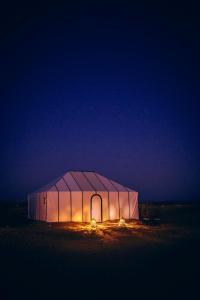 a large tent in the middle of a field at night at Mhamid Sahara Camp - Mhamid El Ghizlane in Mhamid