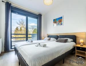 two beds in a bedroom with a large window at Magny's Oasis - DisneyLand 5min - Private Parking - Terrace & Garden in Magny-le-Hongre