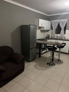 eine Küche mit einem Kühlschrank, einem Tisch und einem Sofa in der Unterkunft Proventures Self-catering House in Ondangwa
