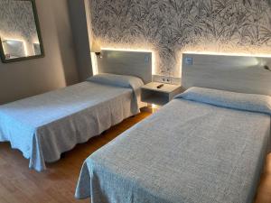 a hotel room with two beds with blue blankets at Miralcampo in Azuqueca de Henares