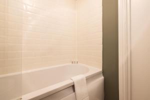 a white bath tub in a bathroom with a towel at The Brockwell Park Place - Bright 2BDR Flat in London