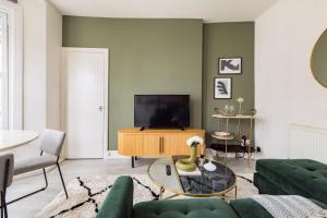 a living room with a couch and a tv at The Brockwell Park Place - Bright 2BDR Flat in London