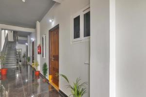 un pasillo con paredes blancas, una puerta y plantas en Super OYO Collection O Rcc Blizz en Kondapur