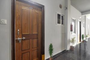 una puerta de madera en un pasillo con una planta en Super OYO Collection O Rcc Blizz en Kondapur