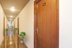 a wooden door in a hallway with a plant at Super OYO Collection O RCC Pristine in Hyderabad