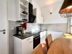 a kitchen with white cabinets and a wooden table at Ferienwohnung an der Schelfkirche in Schwerin