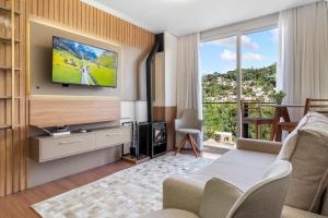 a living room with a television on a wall with a couch at Apartamento Essenza 1 dorm by Achei Gramado in Gramado