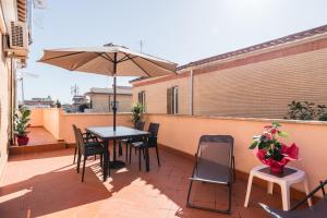 a patio with a table and chairs and an umbrella at 360 GuestHouse - Apartment with terrace in Fiumicino