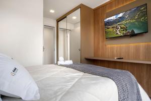 a bedroom with a bed with a tv on the wall at Apartamento Essenza 1 dorm by Achei Gramado in Gramado