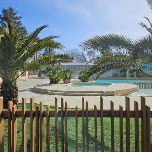 une clôture en bois en face d'un parc planté de palmiers dans l'établissement Vacances en Mobil home à Piriac sur mer, à Piriac-sur-Mer