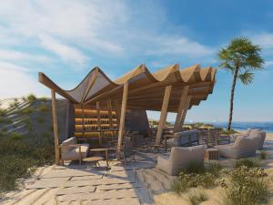 einem Holzpavillon am Strand mit Stühlen und einer Palme in der Unterkunft Ventale Island Breeze Resort in Georgioupoli