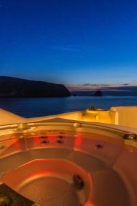 波洛尼亞的住宿－SALT SUITES MILOS，浴缸,晚上可欣赏到海景