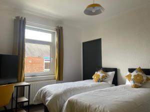 two beds in a room with a window at Quirky and Cosy Two Bed in Ferryhill Near Durham! - Available as individual rooms or the Entire Property! in Ferryhill