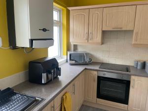 a kitchen with wooden cabinets and a microwave at Quirky and Cosy Two Bed in Ferryhill Near Durham! in Ferryhill